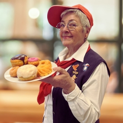 Ehrenamtliche trägt einen Teller voll mit leckeren Donuts